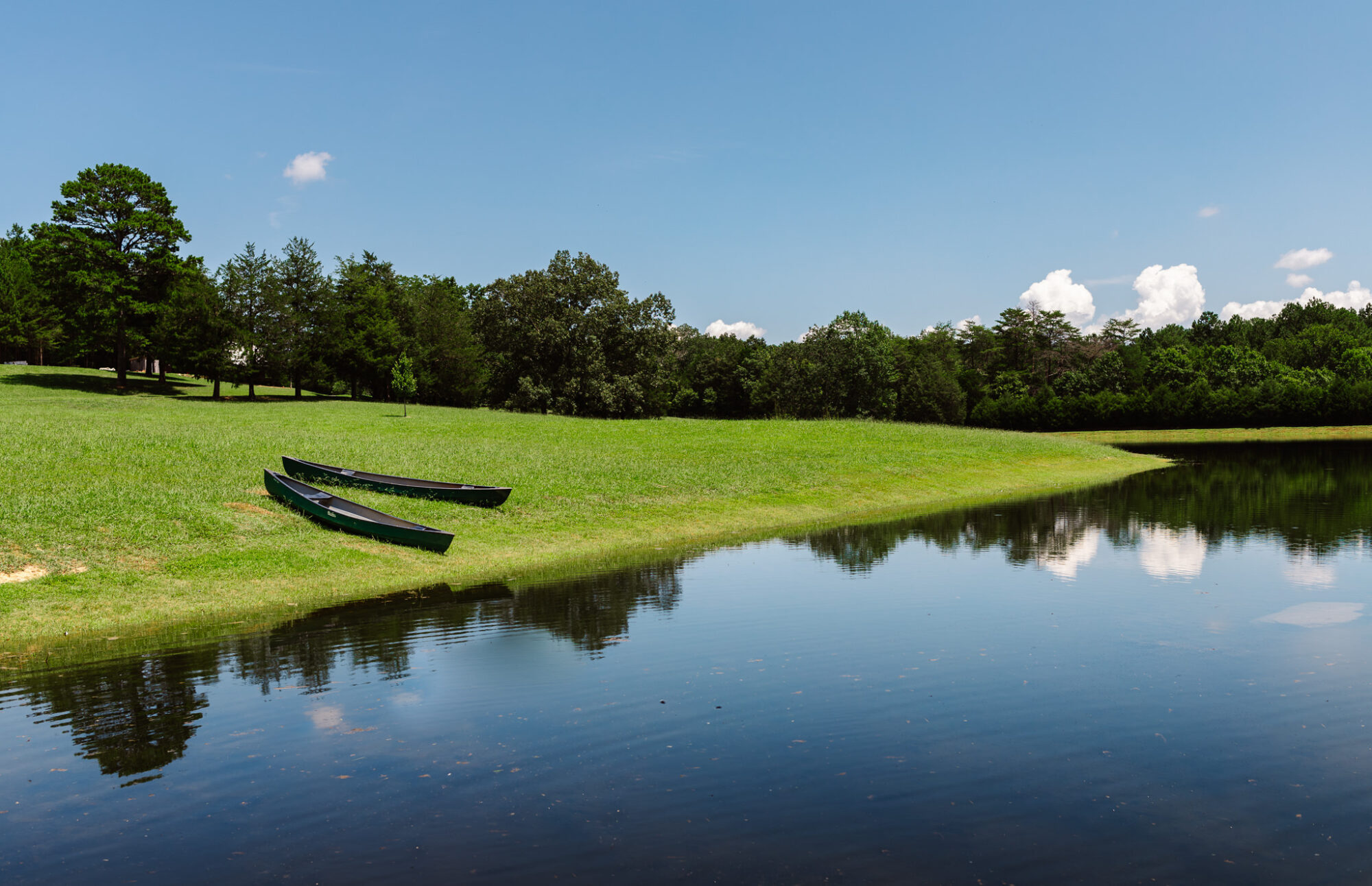 Two canoes sitting on the edge of Lake Angela at Candlelight Forest.